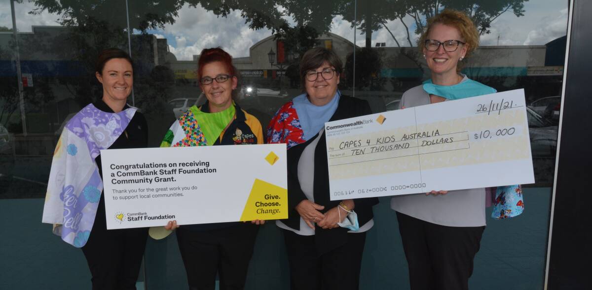 HELPING HAND: Capes 4 Kids' Heather Rogers (second from left) with Commonwealth Bank Dubbo staff Amanda McKay, Louise Lucas and Kylie Egan showing off some of the capes. Picture: ORLANDER RUMING