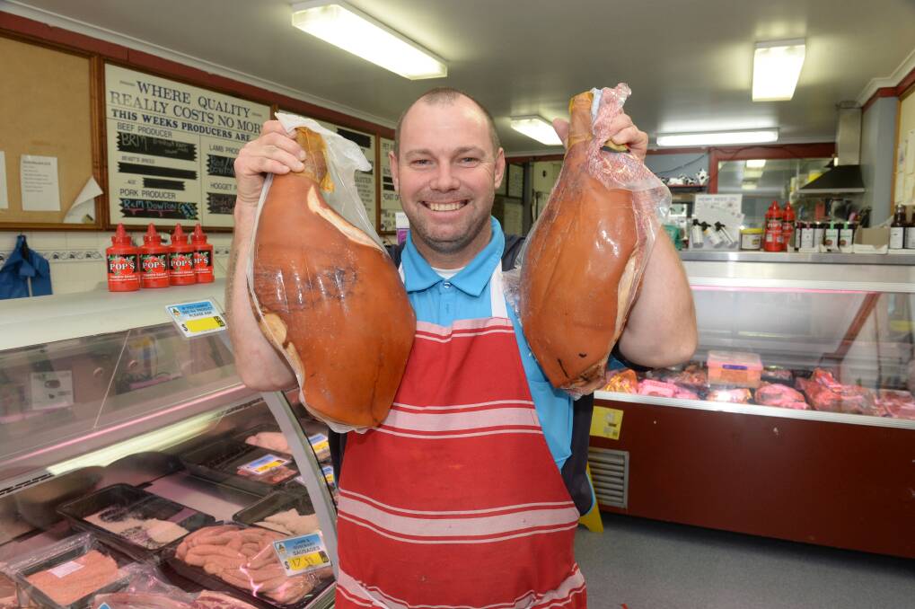Rodney Dowton with two of his homegrown and cured hams in his Wellington butcher shop. He will produce more than 100 hams to sell before Christmas. Photo: Mark Griggs