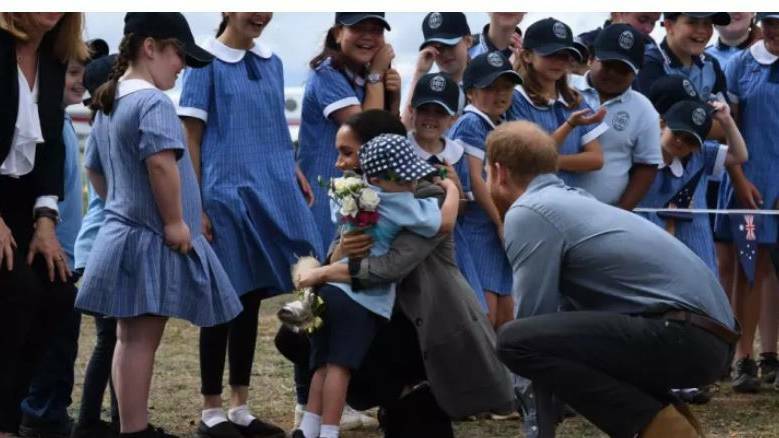 Britain's Prince Harry, the Duke of Sussex looks on as his wife Meghan, the Duchess of Sussex is hugged by student Luke Vincent of Buninyong Public School following their arrival at Dubbo Regional Airport in Dubbo. Photo: AAP Image/Dean Lewins