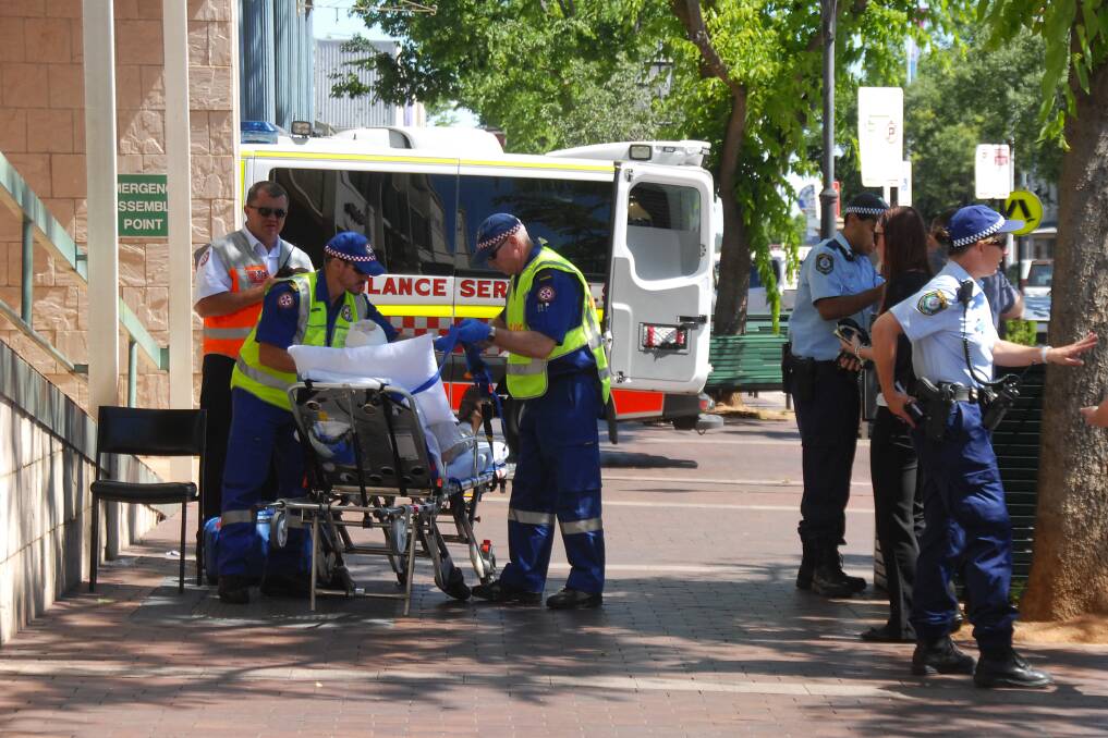 Paramedics attend the injured man on Macquarie Street yesterday afternoon. 	Photo: BELINDA SOOLE