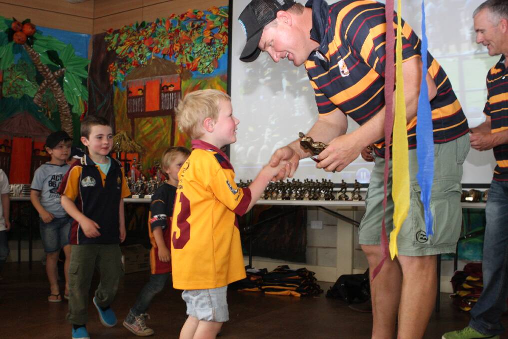 Under-5s coach Shawn Townsend making a presentation to Cooper Townsend with Seb Wilson and Darby Haycock waiting in line.