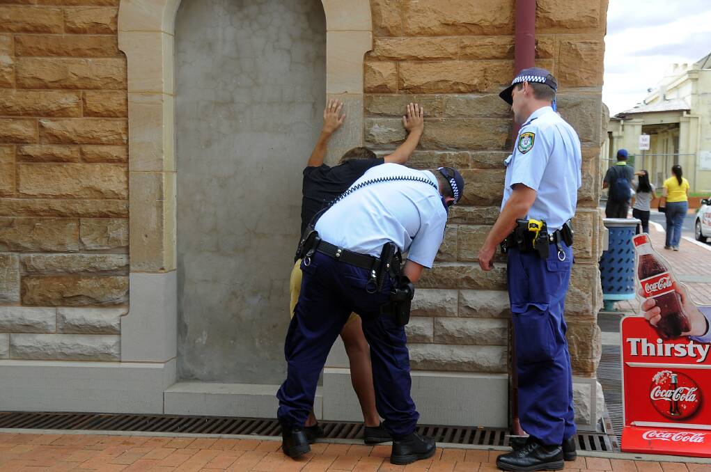 Two police officers search a youth after he arrived in Dubbo yesterdayPHOTO: BELINDA SOOLE