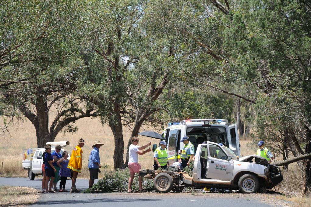 Emergency services help extract an injured man from his ute which crashed into a tree on Benelong Road yesterday. Photo: LISA MINNER