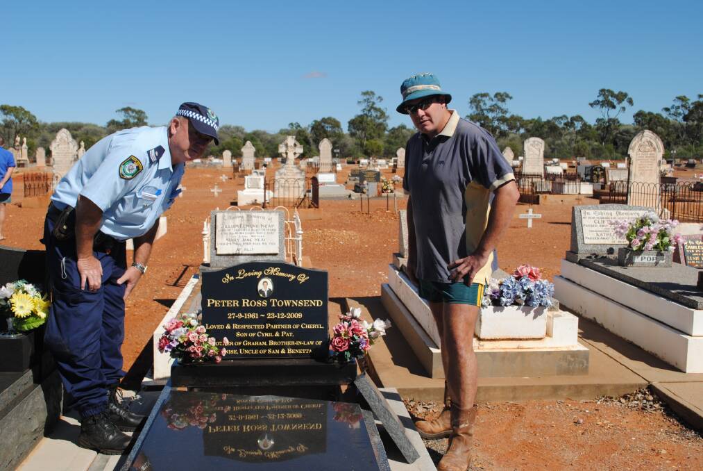 RIGHT: Sergeant John Bennett from Cobar Police mills over the damage with residents whose loved one s graves were desecrated on March 25.