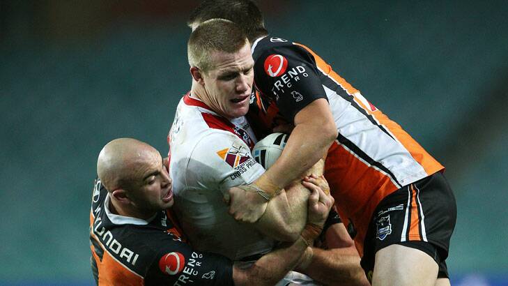 Hunting in a pack … Ben Creagh is rounded up by a trio of Tigers in wet and windy conditions at Allianz Stadium.
