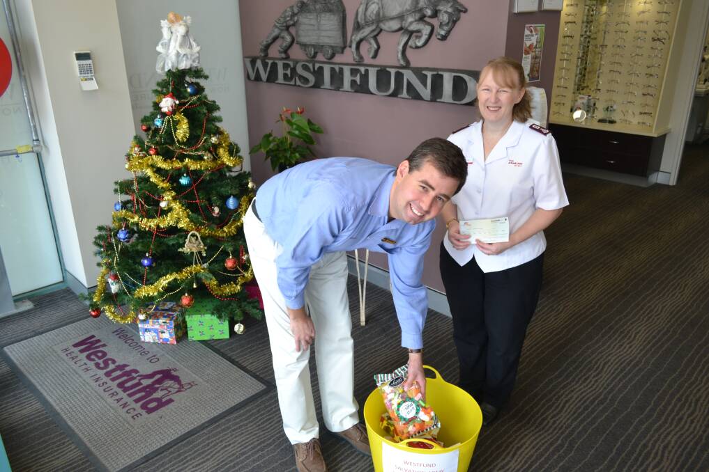 COME AND HELP US: Westfund Dubbo employee Phillip Nott filling the Christmas Appeal bucket as Dubbo's Salvation Army Major Kate Young holds the $500 cheque. PHOTO: ABANOB SAAD.