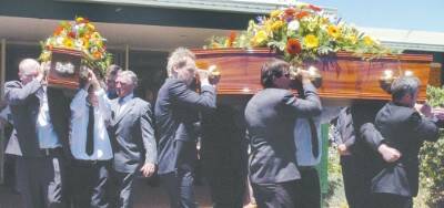 Pallbearers (above) carry the coffins of John and Jackson Pascoe from Dubbo Baptist Church after yesterday’s funeral service, while trucks form a guard of honour (right) at the Western Districts Memorial Park where they were later interred.