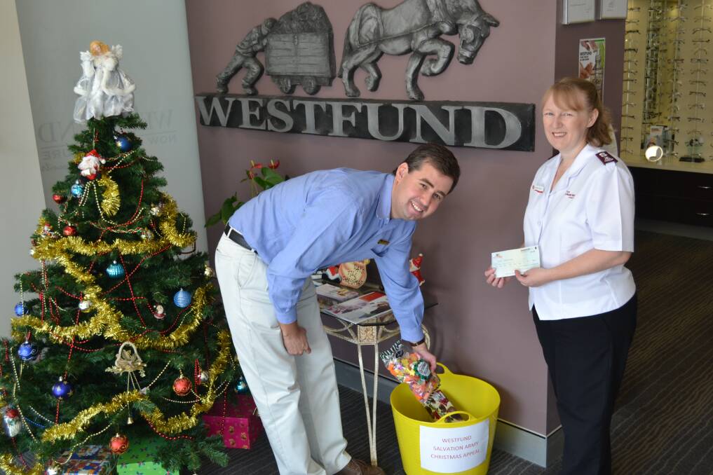 COME AND HELP US: Westfund Dubbo employee Phillip Nott filling the Christmas Appeal bucket as Dubbo's Salvation Army Major Kate Young holds the $500 cheque. PHOTO: ABANOB SAAD.