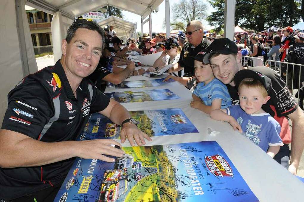 Craig Lowndes signs some posters for Nathaniel Mason with his nephews, Dominic(6) & Aiden Poisel(4)(from Bathurst).Photo: CHRIS SEABROOK 100913cdrivrs1