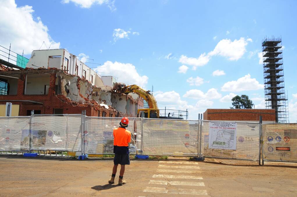 Checking out the demolition work at Dubbo Base Hospital yesterday morning are Health Infrastructure senior project director Bruno Zinghini (left) and hospital general manager Debbie Bickerton (right), in the company of Scott Galloway, senior project manager for TSA Management, the company managing the redevelopment. INSET: Machinery was brought in yesterday afternoon for the final push in the demolition of the nurses' quarters. Photo: BELINDA SOOLE